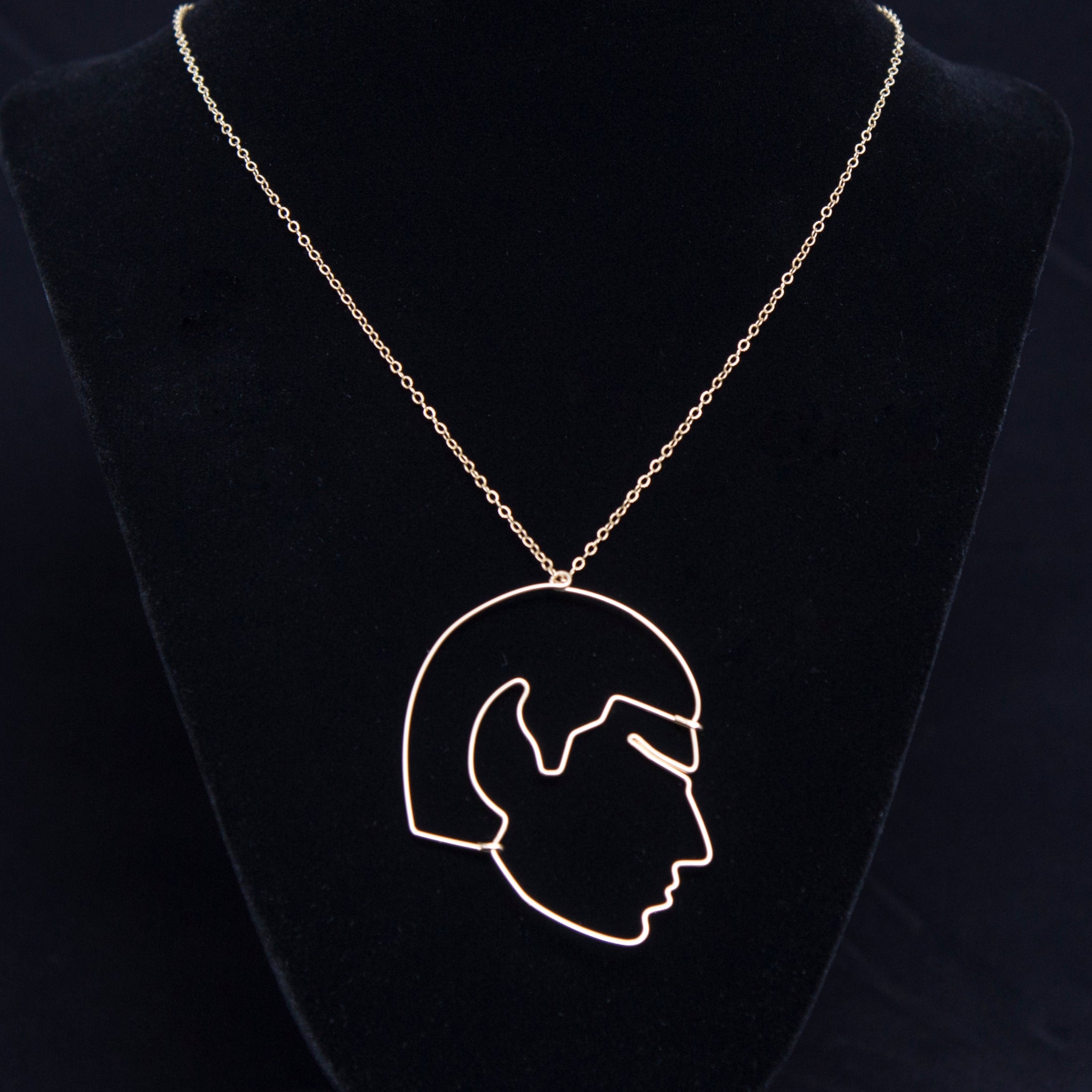 Necklace with a pendant of a profiled Mr. Spock on a black velvet stand against a dark background
